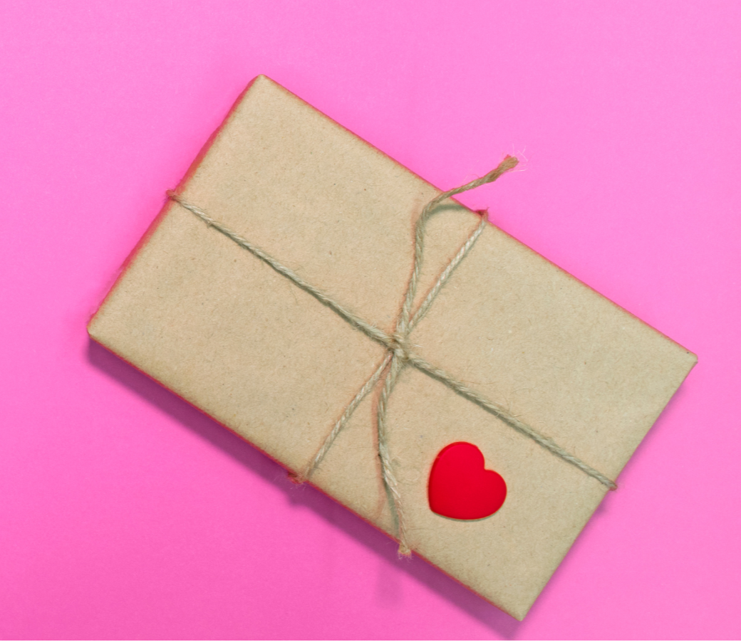 Kraft paper envelope tied with string on a pink background
